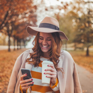 Woman using phone while walking outside. Fashionably dressed