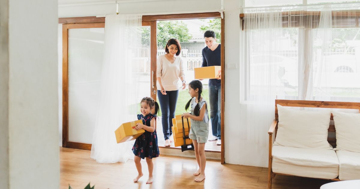 Family moving into new home carrying boxes